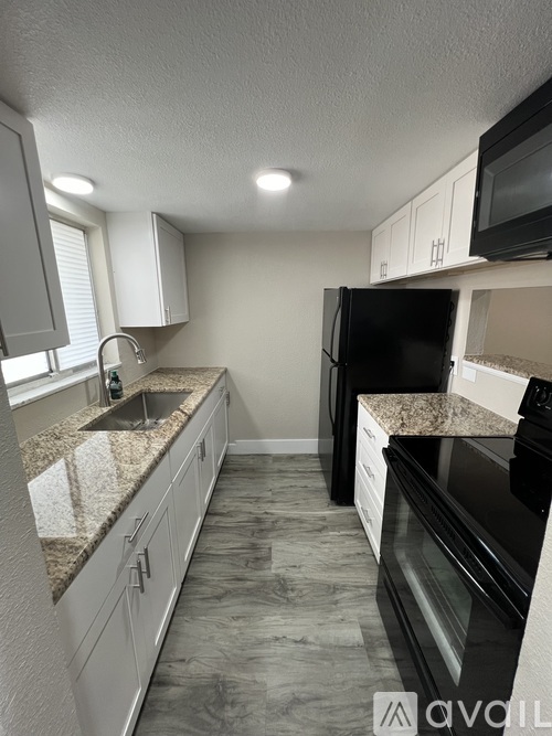 A kitchen with granite countertops and black appliances.