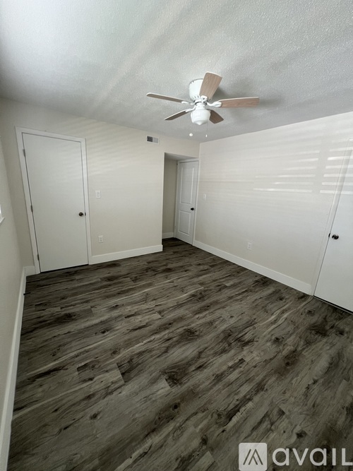 A room with a ceiling fan and wooden flooring.