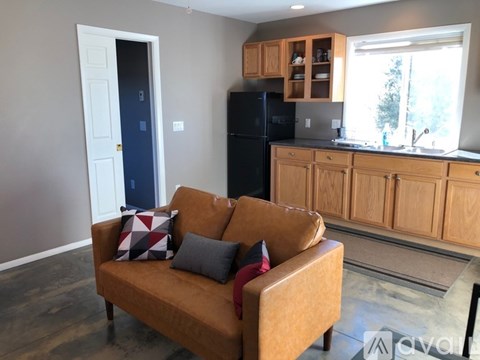 A living room with a brown couch and a black refrigerator.