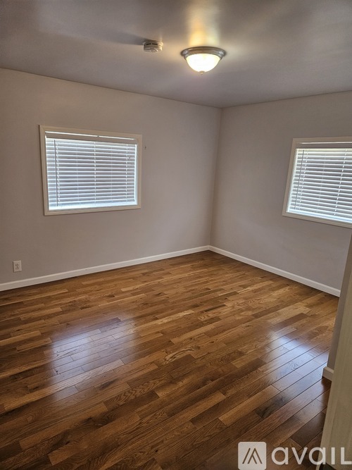 A room with wooden floors and two windows.
