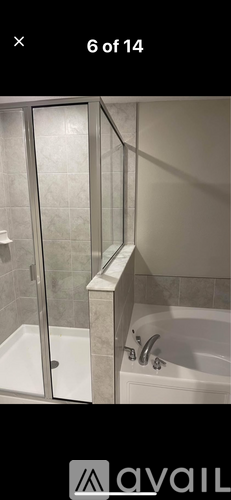 A bathroom with a glass shower door and a white bathtub.