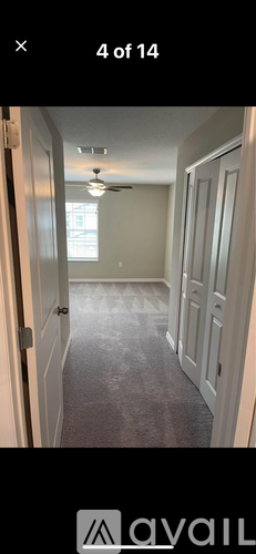 A long hallway with a carpeted floor and a ceiling fan.