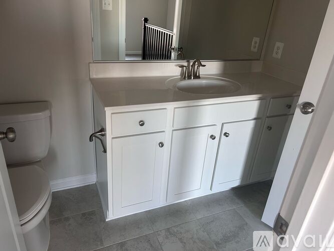 A bathroom with a toilet, sink, and cabinets.