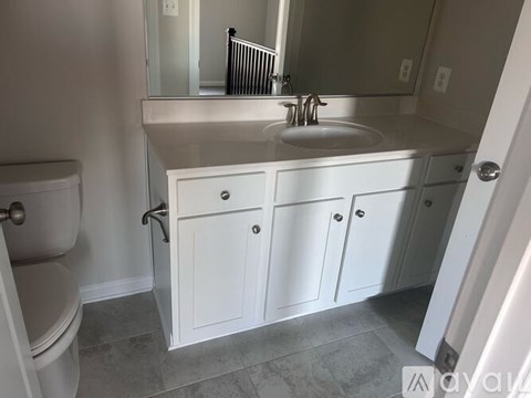 A bathroom with a toilet, sink, and cabinets.
