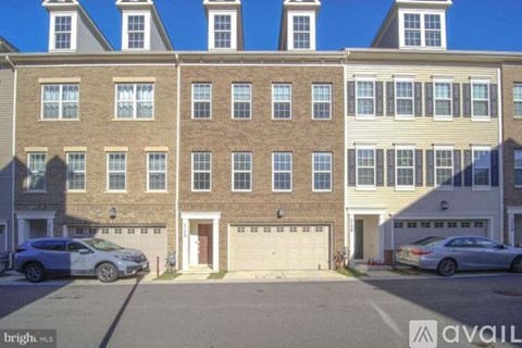 A row of townhouses with garages and cars parked in front.