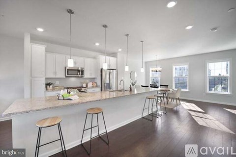 A modern kitchen with white cabinets and a large island with bar stools.
