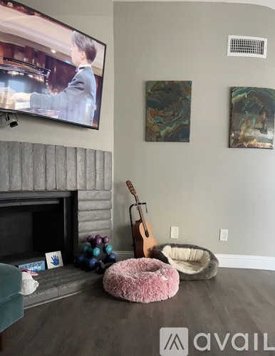 A living room with a fireplace, a television, and a guitar.