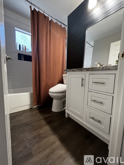 A bathroom with a toilet, sink, and brown curtains.