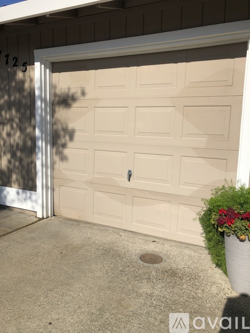 A white garage door with a black handle and a number 1725 on the wall above it.