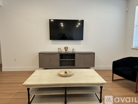 A modern living room with a flat screen TV mounted on the wall above a cabinet and a coffee table in the foreground.