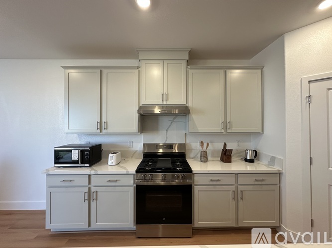 A kitchen with white cabinets and appliances.