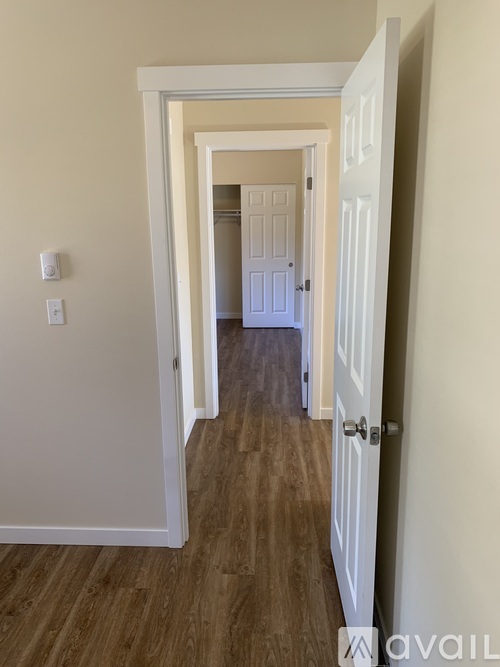 A hallway with a white door and wooden floor.
