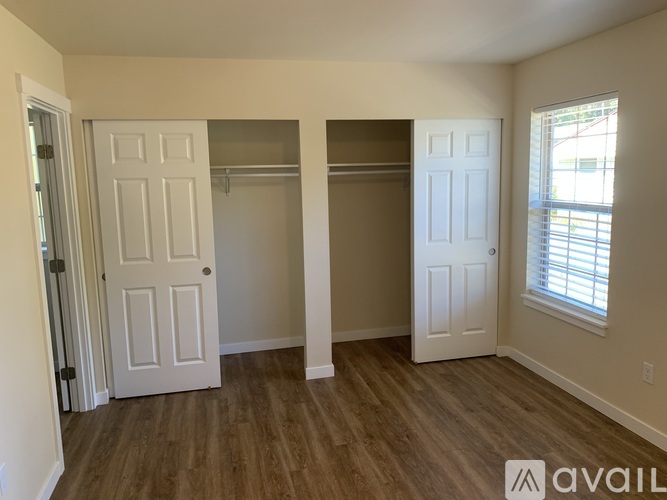 A room with two white doors and a window with blinds.