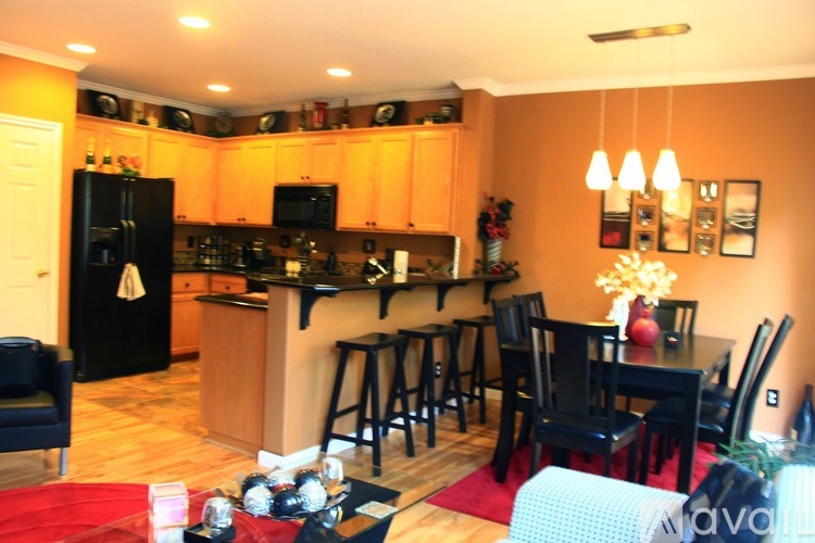 A kitchen with a black fridge and a dining table with chairs.