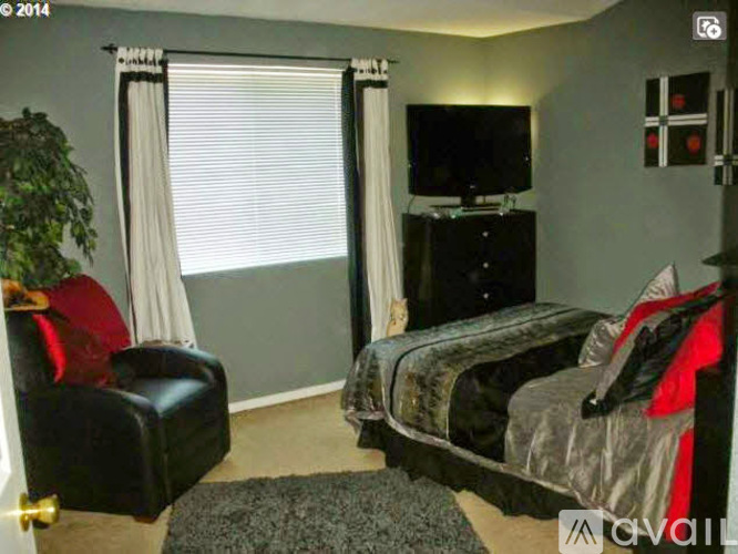 A bedroom with a bed, chair, and television.