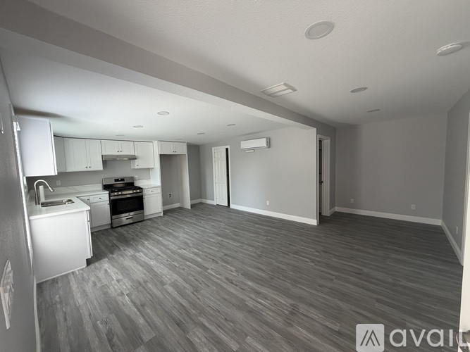 A spacious kitchen with white appliances and a grey floor.