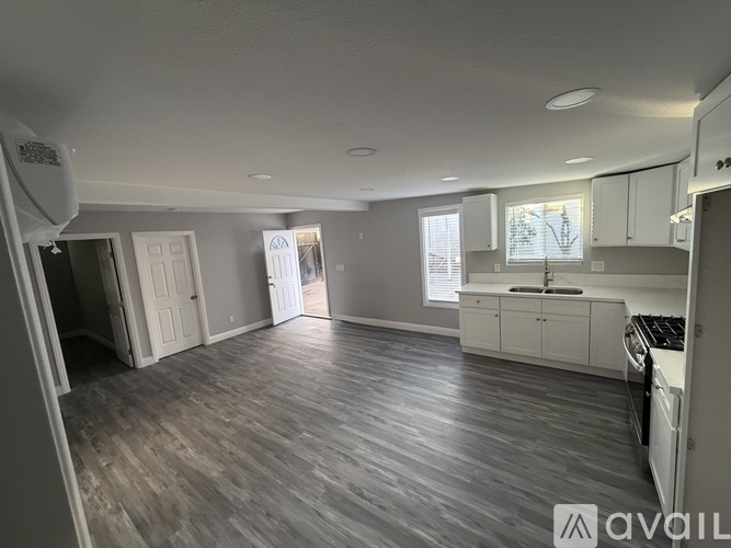 A spacious kitchen and living room with hardwood floors and white cabinetry.