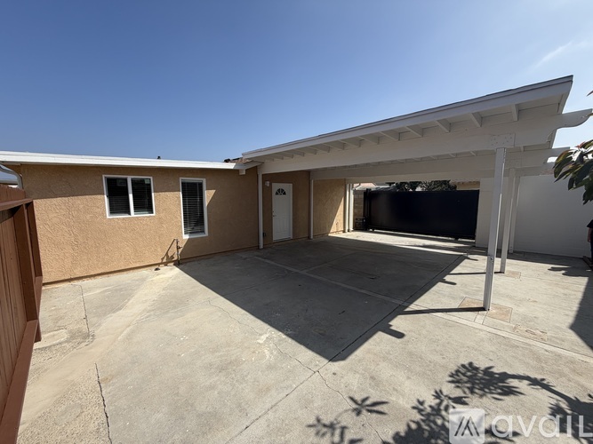 A house with a brown exterior and a white roof has a patio with a TV on it.
