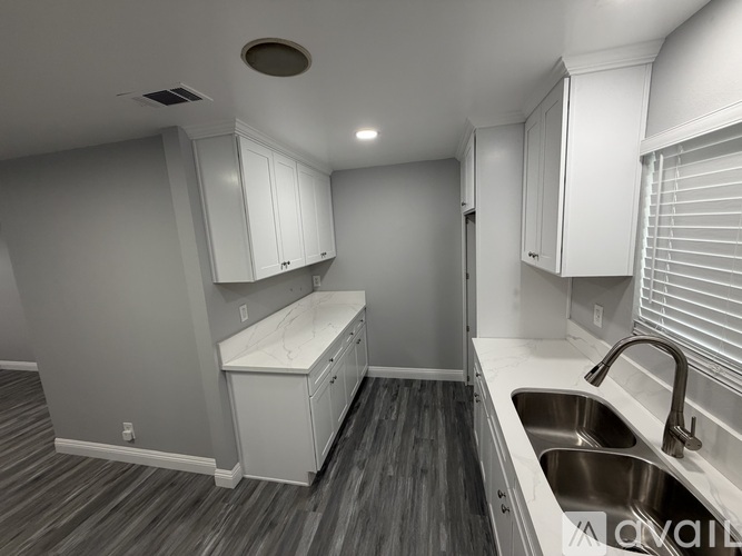 A kitchen with white cabinets and a wooden floor.