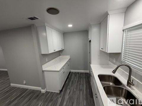 A kitchen with white cabinets and a wooden floor.