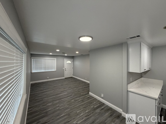 A spacious room with wooden flooring and white walls.