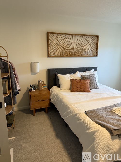 A bedroom with a large bed and a wooden nightstand.