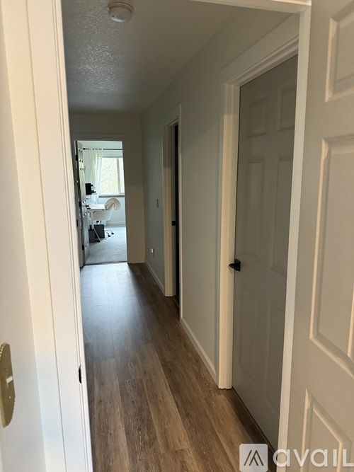 A hallway with a white door and a wooden floor.