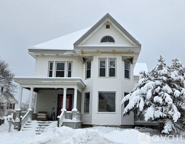 A white house with a snow-covered tree in front.