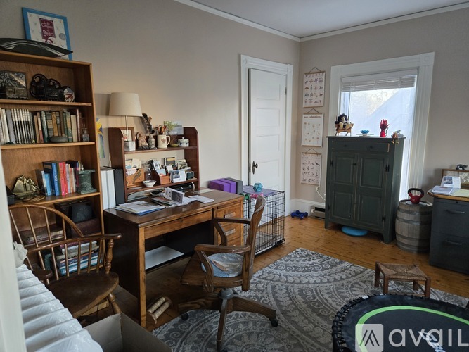 A room with a desk, chairs, and a bookshelf.