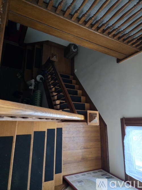 A stairway with a wooden handrail and steps leading up to a door.