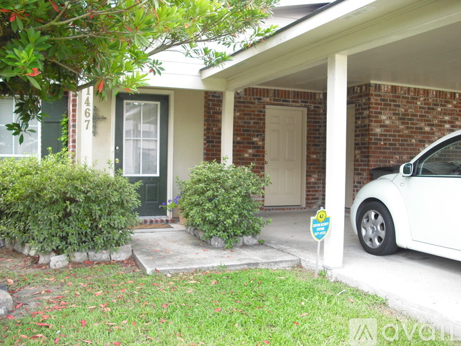 A white car is parked in front of a house with a green door.