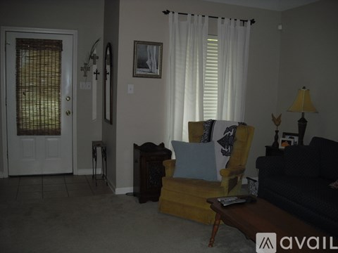 A living room with a yellow chair and a black couch.