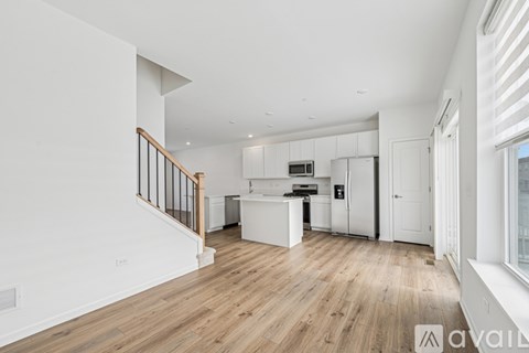 A spacious kitchen with white cabinets and a wooden floor.