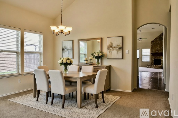 A dining room with a table set for four and a chandelier hanging from the ceiling.