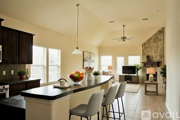 A kitchen with a black countertop and white chairs.