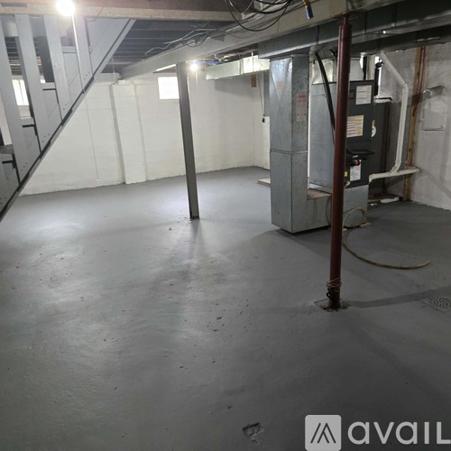 A spacious basement with a concrete floor and a staircase on the left side.