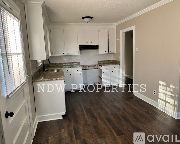 A kitchen with white cabinets and a wooden floor.