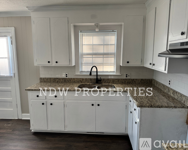 A kitchen with white cabinets and a granite countertop is available for rent.