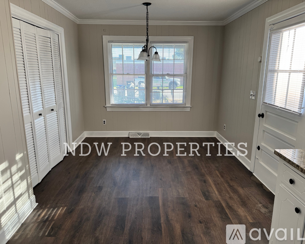 A room with wooden floors and a window with blinds.
