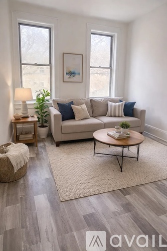 A living room with a grey couch, a round table, and a rug.