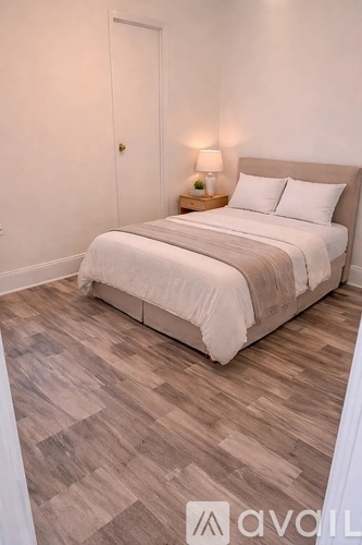 A bedroom with a bed, pillows, and a lamp.
