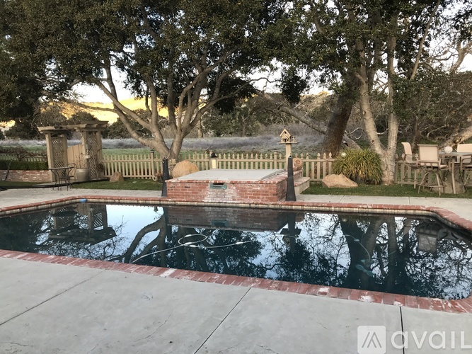 A pool surrounded by a fence and trees.