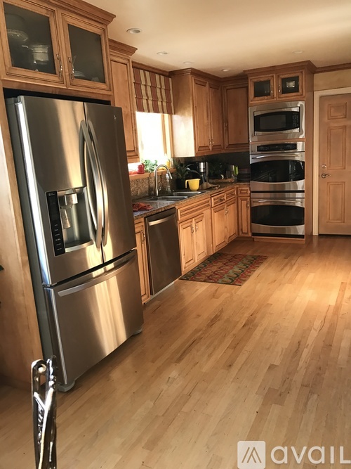 A kitchen with wooden cabinets and a stainless steel refrigerator.