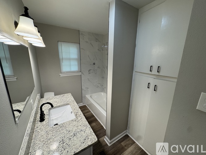 A bathroom with a marble countertop and a white cabinet.