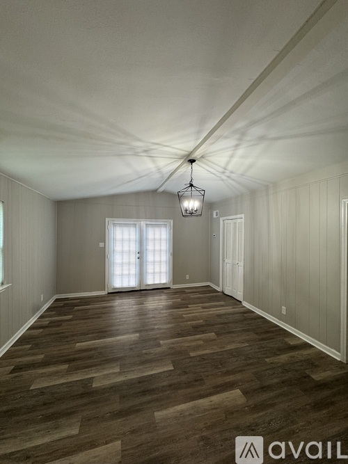 A room with wooden flooring and a hanging light fixture.