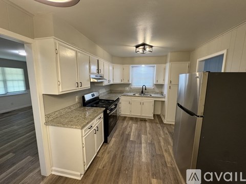 A kitchen with white cabinets and a black refrigerator.