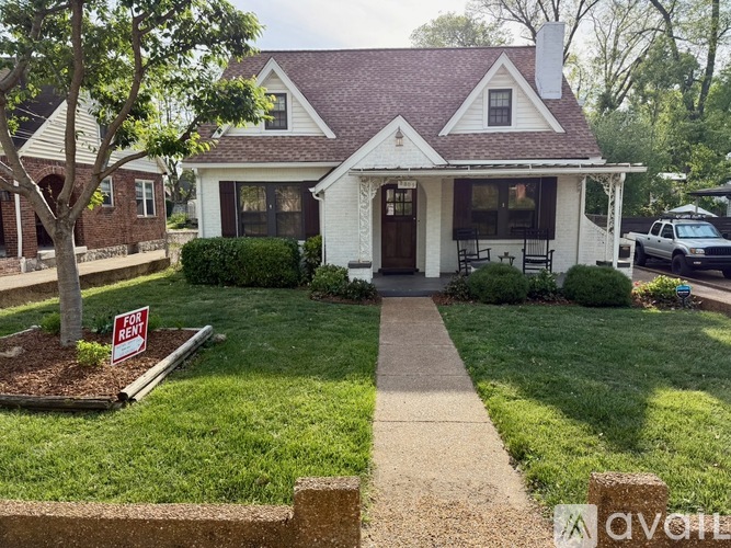 A house with a red roof and a white front porch is for sale.