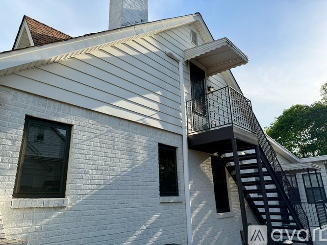 A white house with a black staircase and a balcony.