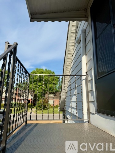A black metal gate leads to a house with a white wall.
