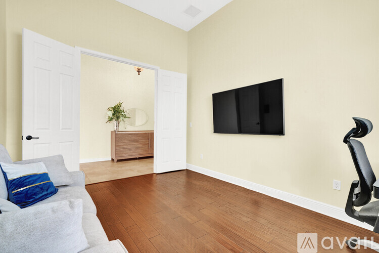 A living room with a white couch and a black TV mounted on the wall.